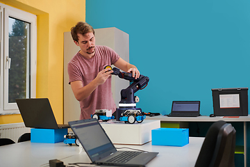 Image showing A student testing his new invention of a robotic arm in the laboratory, showcasing the culmination of his research and technological prowess.