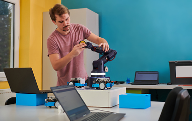 Image showing A student testing his new invention of a robotic arm in the laboratory, showcasing the culmination of his research and technological prowess.