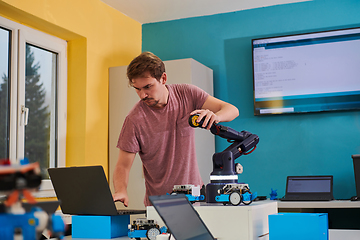 Image showing A student testing his new invention of a robotic arm in the laboratory, showcasing the culmination of his research and technological prowess.
