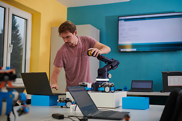 Image showing A student testing his new invention of a robotic arm in the laboratory, showcasing the culmination of his research and technological prowess.