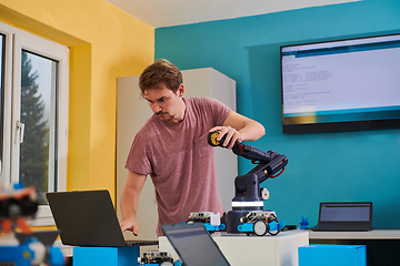 Image showing A student testing his new invention of a robotic arm in the laboratory, showcasing the culmination of his research and technological prowess.