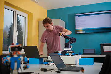 Image showing A student testing his new invention of a robotic arm in the laboratory, showcasing the culmination of his research and technological prowess.