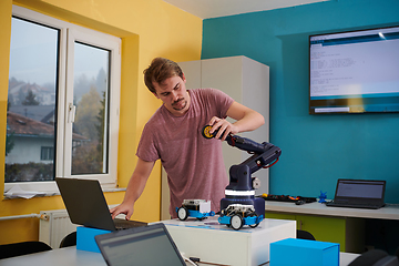 Image showing A student testing his new invention of a robotic arm in the laboratory, showcasing the culmination of his research and technological prowess.