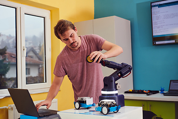 Image showing A student testing his new invention of a robotic arm in the laboratory, showcasing the culmination of his research and technological prowess.