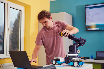 Image showing A student testing his new invention of a robotic arm in the laboratory, showcasing the culmination of his research and technological prowess.