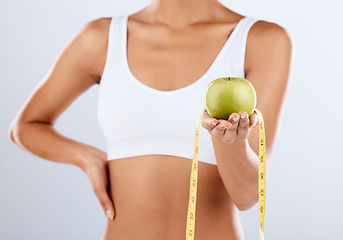 Image showing Diet, apple and tape measure with a fitness black woman in studio on a gray background for healthy eating. Exercise, fruit and wellness with a female posing to promote a lifestyle of health or detox