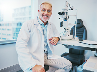 Image showing Optometry, healthcare and portrait of a male optometrist sitting by equipment in a optical clinic. Vision, medical and senior man eye care specialist with a retinoscope machine in a optic store.