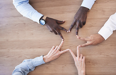 Image showing Hands, star and collaboration overhead with a business team in the office sitting at a boardroom table. Hand sign, shape or teamwork with a man and woman employee group meeting for strategy at work