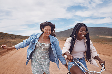 Image showing Bike, girl friends and happy road trip fun of women outdoor on a desert path on summer vacation. Cycling, running and freedom of young people together with bicycle transportation feeling free