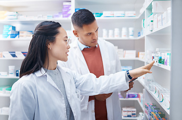 Image showing Pharmacist, coworkers and conversation with pills, medicine and inventory for stock with discussion. Pharmacy, man or Asian woman with healthcare, prescriptions or coaching for new process or system