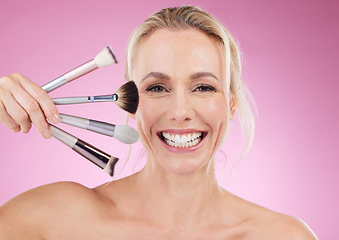 Image showing Portrait, makeup and cosmetic brushes with a mature woman in studio on a pink background to promote a product. Face, happy and cosmetics with an attractive older female posing for beauty treatment