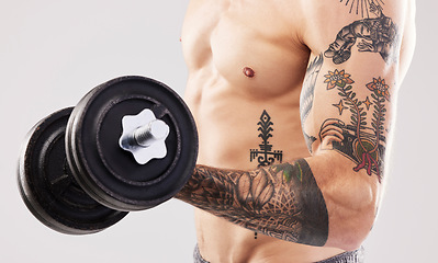 Image showing Arm muscle, dumbbell and man with tattoo and workout in a studio for fitness, exercise and power. Gray background, isolated and gym model weightlifting, bodybuilding and doing body wellness training