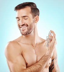 Image showing Man, beauty and perfume spray in studio isolated on a blue background for wellness. Fragrance, cologne and happy male model with product for fresh scent, aroma and self care, hygiene and grooming.