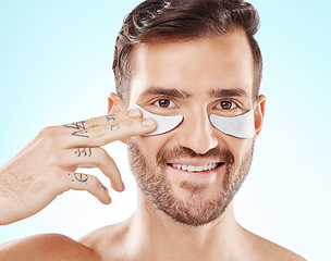 Image showing Face, skincare and man with eye patches in studio isolated on a blue background. Beauty, portrait and male model with pad product for dermatology, cosmetics and facial treatment, wellness and health