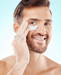 Image showing Skincare, face and man with eye patch in studio isolated on a blue background. Beauty, portrait and male model with pad product for dermatology, cosmetics and facial treatment, wellness and health.