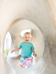 Image showing Child playing on outdoor playground. Toddler plays on school or kindergarten yard. Active kid on stone sculpured slide. Healthy summer activity for children. Little boy climbing outdoors.