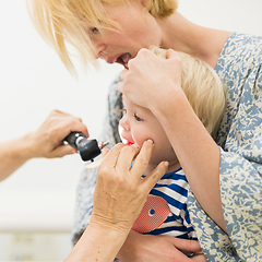 Image showing Infant baby boy child being examined by his pediatrician doctor during a standard medical checkup in presence and comfort of his mother. National public health and childs care care koncept.