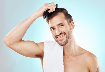 Image showing Hair care, man in portrait and beauty with comb and grooming with hygiene on blue background. Cosmetics, clean and fresh with hairstyle, wellness and routine with skin, glow and towel with skincare