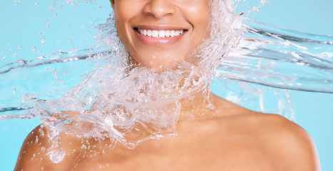 Image showing Skincare, clean and smile of a woman with a water splash isolated on a blue background in studio. Health, wellness and mouth, face and happy model on a backdrop for a shower, cleaning and grooming