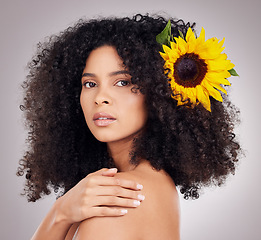 Image showing Portrait, serious or face of black woman with sunflower in hair in studio for spring time, luxury spa or self care. Aesthetic, beauty facial or girl model with plant for skincare, cosmetic or makeup