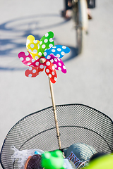 Image showing Colorful pinwheel attached to bicycle basket to entertain toddler child riding on front child seat on bike in summer.
