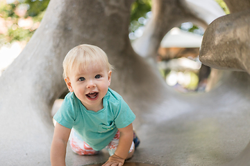 Image showing Child playing on outdoor playground. Toddler plays on school or kindergarten yard. Active kid on stone sculpured slide. Healthy summer activity for children. Little boy climbing outdoors.