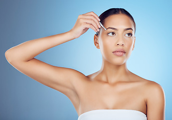 Image showing Tweezers, eyebrow and woman in studio for beauty, grooming and hygiene on blue background space. Hair removal, epilation and brow tool by girl skin model relax with luxury, product and cosmetic care