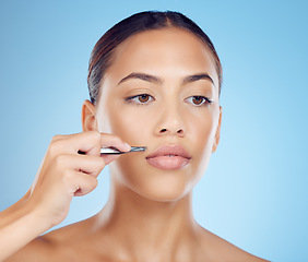 Image showing Tweezer, lip and hair removal with woman in studio for beauty, grooming and hygiene on blue background. Facial, moustache and product or tool for girl model with mouth, hairs and cleaning isolated