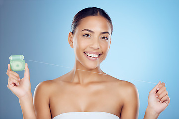 Image showing Floss product, dental portrait and woman on studio mockup for teeth, mouth cleaning and marketing. Happy female model, flossing thread and blue background for tooth cosmetics, wellness and healthcare