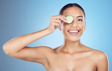 Image showing Cucumber, woman and portrait face for beauty, clean wellness diet and blue studio background. Happy model, eyes and green fruits cosmetics for detox, facial skincare and healthy aesthetic benefits