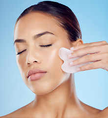 Image showing Woman, beauty and face massage with gua sha, facial product or aesthetic skincare in studio. Young model, crystal stone tools and wellness for natural cosmetics, rose quartz dermatology or body salon