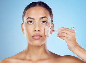 Image showing Woman, portrait and face roller for beauty, facial product and aesthetic skincare in studio. Young model, crystal stone treatment and wellness for natural cosmetics, rose quartz dermatology and salon