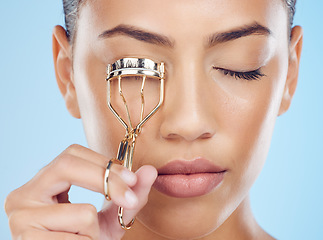 Image showing Cosmetics, routine and woman with an eyelash curler isolated on a blue background in a studio. Skincare, beauty and face of model with a metal product for lashes, makeup and mascara on a backdrop