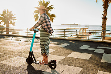 Image showing Electric scooter, retirement and woman riding on sidewalk at tropical island beach resort for happy vacation. City, street and eco friendly transport, fun for grandma on escooter on holiday in Hawaii