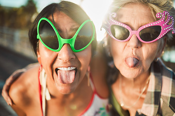 Image showing Funny, selfie and tongue out by senior women with sunglasses outdoors for travel, break and bonding on blurred background. Emoji, face and crazy elderly friends pose for photo, profile picture or fun