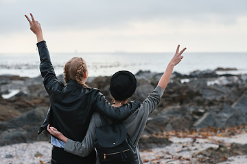 Image showing Women, back and friends at beach with peace sign, bonding and hugging. Freedom, travel and girls or females with v gesture or emoji, embrace and enjoying quality time together by seashore or ocean