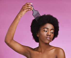 Image showing Black woman, hairstyle or afro brushing on beauty studio background in relax grooming routine, texture maintenance or wellness. Model, comb or natural hair growth and skincare makeup on isolated pink