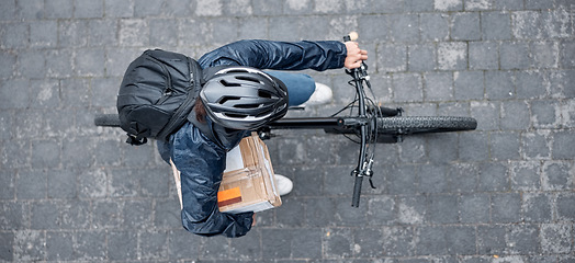 Image showing Top view, bicycle and delivery man with box in city for package, logistics and shipping. Courier, eco friendly transport and male bike driver with cargo, stock or goods for ecommerce on road in town.