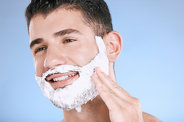 Image showing Facial, foam on beard and man with smile and hand on face with product placement and mockup in studio. Shaving cream, hair and skincare for happy male model grooming, isolated on blue background.