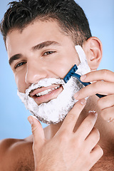 Image showing Smile, foam and man with beard shaving with razor in hand, facial and product placement in studio mock up. Shave cream on face, hair and skincare for happy male model isolated on blue background.