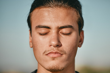 Image showing Zen, meditation and face of man meditating closed eyes outdoors for calm, peace and is mindful with blue sky background. Person, relax and spiritual male with faith in wellness and health