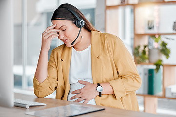 Image showing Call center, headache and pregnancy, woman at desk with hand on stomach, exhausted in office with headset. Burnout, pain and pregnant telemarketing consultant with anxiety from deadline time stress.