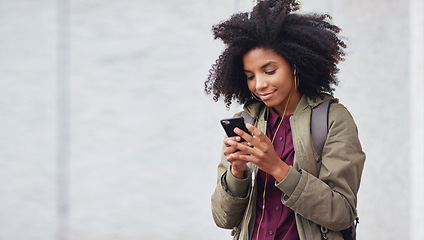 Image showing Black woman, phone and earphones in city, texting and smile for flirt chat, online date or meme on app. Young gen z girl, african student and travel in metro with smartphone for social media with iot