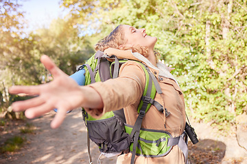 Image showing Woman hiking, freedom and open hands in nature with happiness, wellness and outdoor adventure in summer. Happy hiker girl, free and smile sunshine in woods, forrest and walk with backpack on holiday