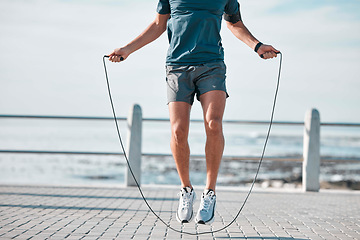 Image showing Jump rope, fitness and man by a sea promenade with training, sports and exercise equipment. Health, jumping and body wellness of a athlete doing cardio jump for active lifestyle by the ocean