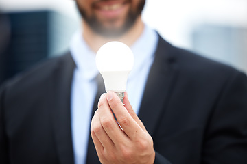 Image showing Businessman, hands and light bulb with idea in the city for solution, eco friendly or renewable energy. Hand of male employee holding lamp for creativity, ideas or power saving element on mockup