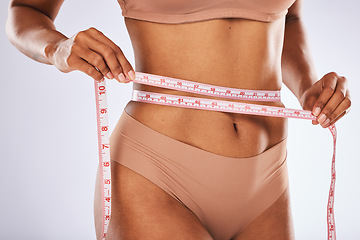 Image showing Waist, tape and woman measuring body to lose weight isolated on grey studio background. Fitness, health and hands of a girl on a diet to measure stomach for exercise results and slimming on backdrop