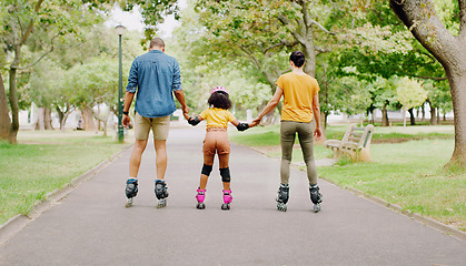 Image showing Family, park and holding hands to rollerskate with girl child with care, learning and support. Interracial parents, black man and woman with kid, back and helping hand on road for outdoor holiday