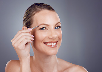 Image showing Eyebrows, grooming and portrait of a woman with a tweezers isolated on a grey studio background. Beauty, treatment and happy model plucking hair from face for shaping and routine on a backdrop