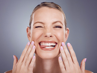Image showing Skincare, comic and portrait of a woman touching face isolated on a grey studio background. Funny, makeup and a model for cosmetics, beauty expression and crazy on a backdrop with tongue out